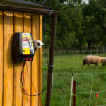 Električni pastir Horizont Hotshock N500 fiksiran na leseni objekt. Priklopljen je na električno ombrežje ter varuje drobnico.